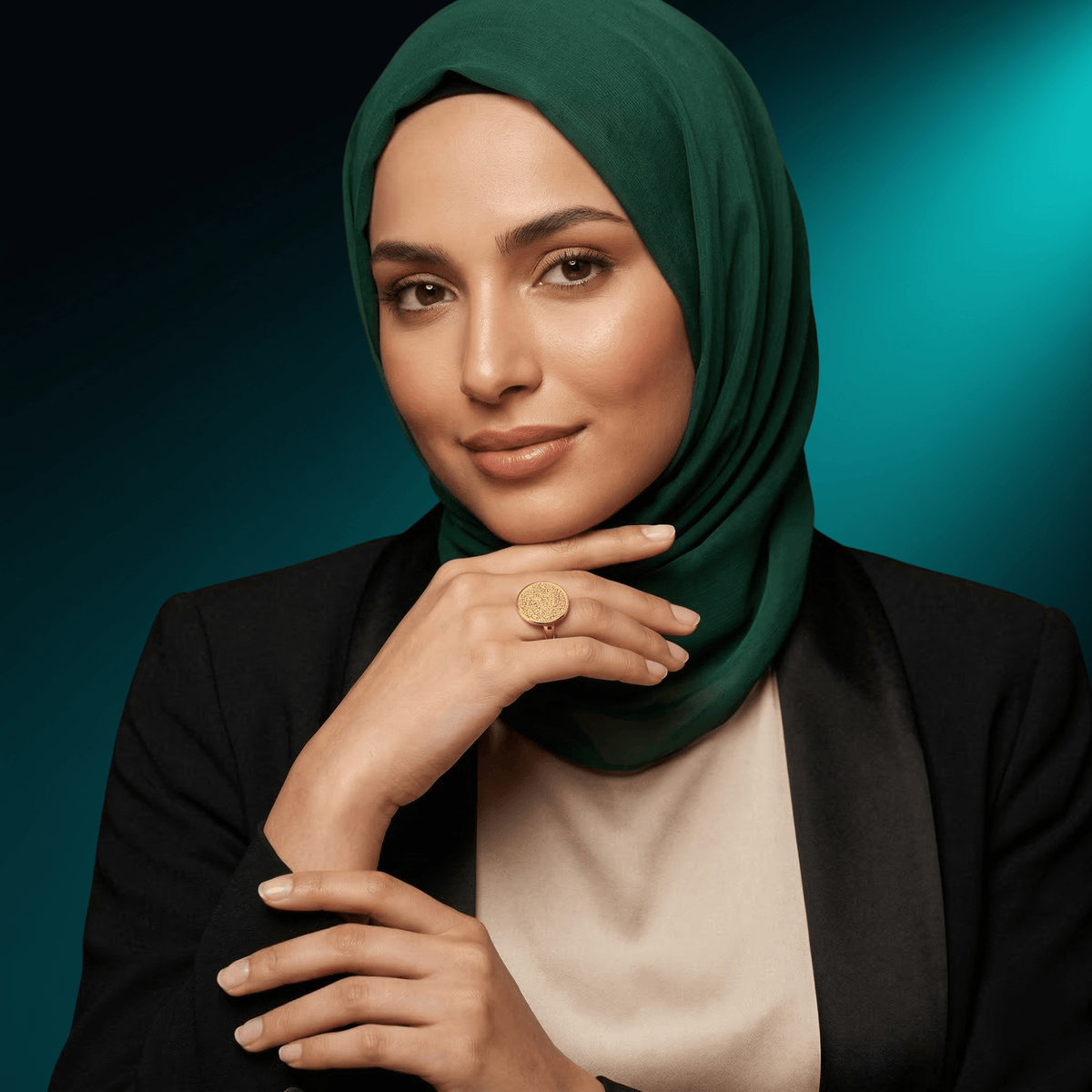 Woman in a green hijab wearing the NUUR Ayatul Kursi gold ring, hand at her chin