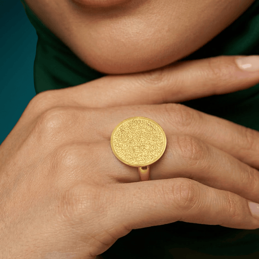 Close-up of the NUUR Ayatul Kursi gold ring worn on the middle finger, engraving in full view