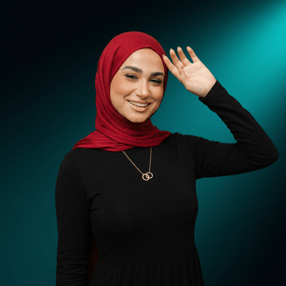 Woman in a red hijab wearing the NUUR Sanad interlocking ring necklace